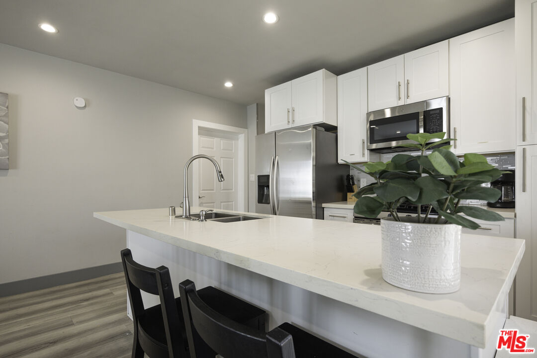 1559 1/2 South Harvard Boulevard Los Angeles, CA 90006 - Photo 4 of 16 a kitchen with a dining table chairs and refrigerator
