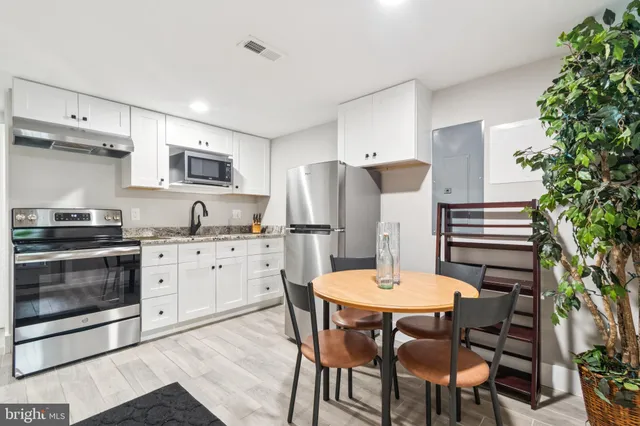 a kitchen with stainless steel appliances a stove a table and chairs