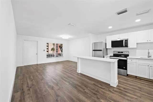 a kitchen with granite countertop a stove top oven a sink dishwasher and a refrigerator with wooden floor