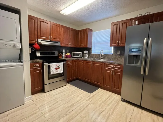 a kitchen with stainless steel appliances granite countertop a refrigerator a stove a sink and a microwave