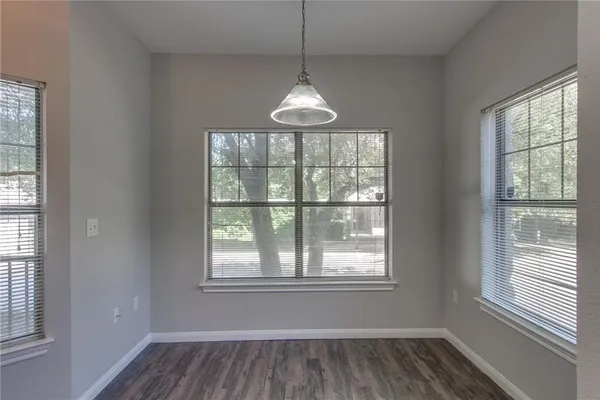 a room with wooden floor chandelier and windows