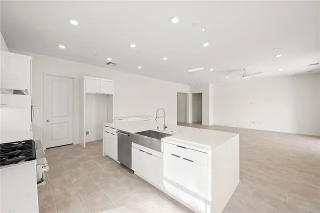 a large white kitchen with stainless steel appliances granite countertop a sink and a stove
