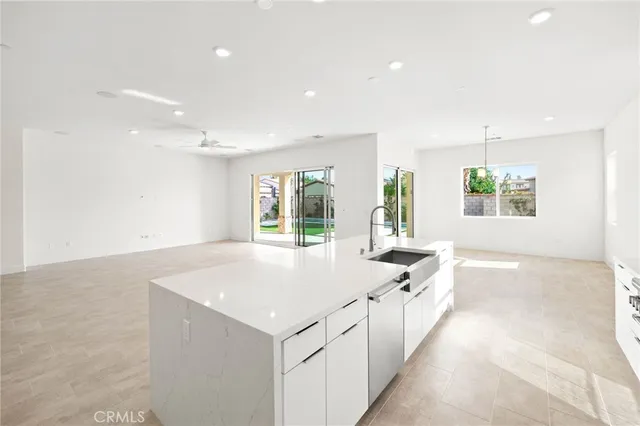a large white kitchen with granite countertop a sink and dishwasher next to a large window