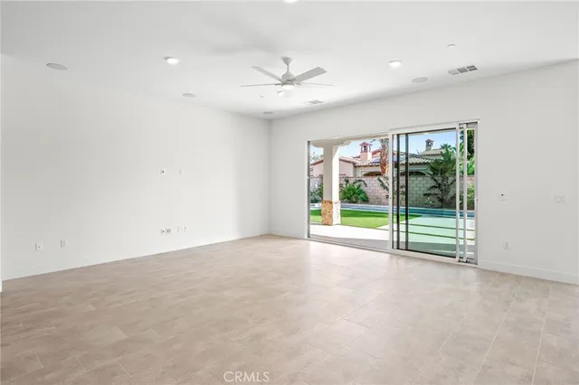 a view of an empty room with window ceiling fan