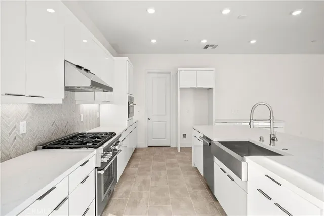 a kitchen with stainless steel appliances a sink stove and cabinets