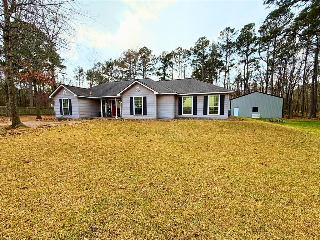 a view of a house with a yard and large trees