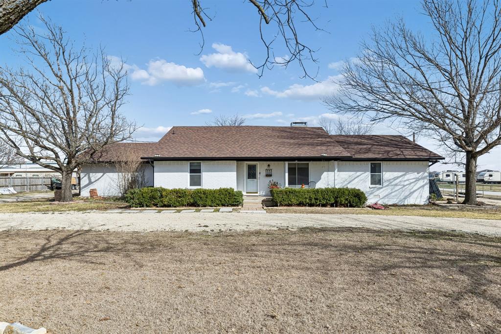 a front view of a house with a dirt yard and a large tree