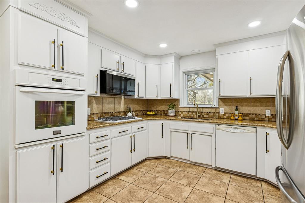 1012 Cowling Road Sanger, TX 76266 - Photo 13 of 40 a kitchen with stainless steel appliances granite countertop a stove top oven a sink and white cabinets