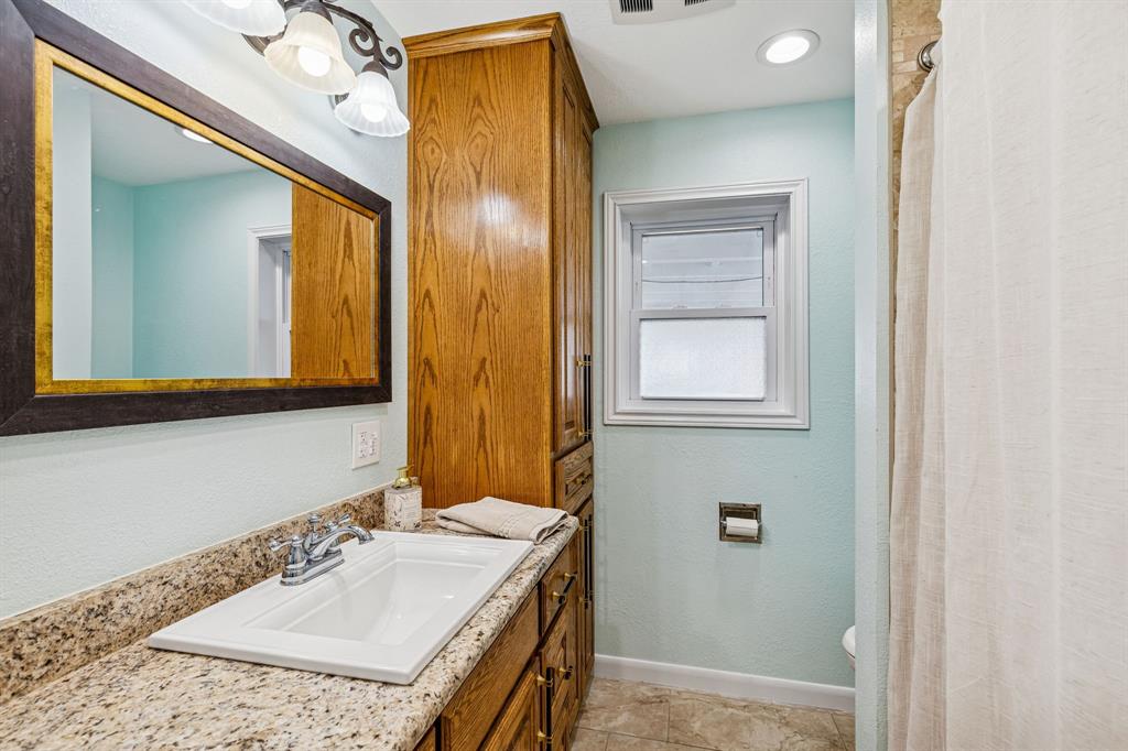 1012 Cowling Road Sanger, TX 76266 - Photo 23 of 40 a bathroom with a granite countertop sink and a mirror