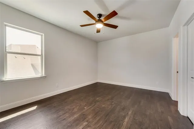an empty room with wooden floor fan and windows