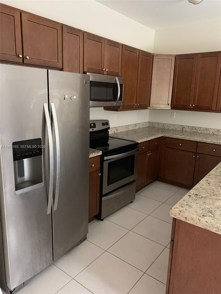 8440 West McNab Road, Unit 8440 Fort Lauderdale, FL 33321 - Photo 19 of 22 a kitchen with granite countertop a refrigerator and a stove top oven