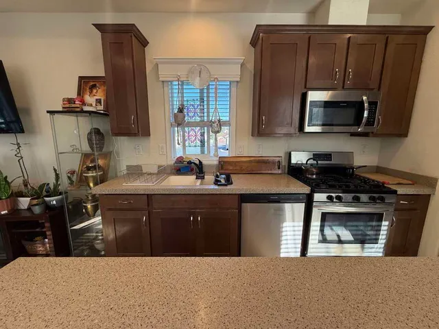 a kitchen with stainless steel appliances a sink a stove a microwave a sink and a refrigerator