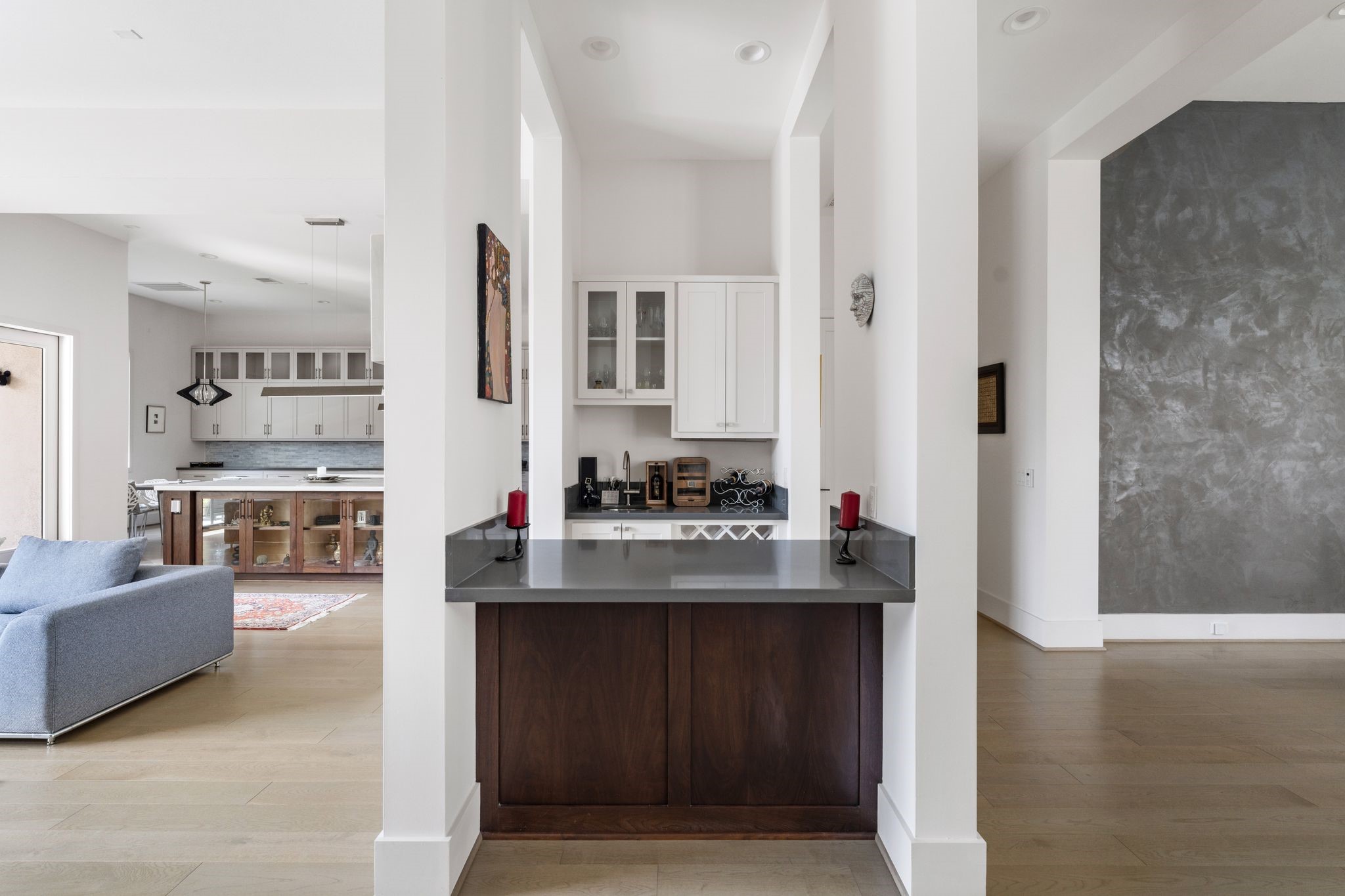 5427 Maple Street Houston, TX 77096 - Photo 13 of 46 A compact built-in wet bar area features upper cabinetry with glass fronts and a durable countertop, positioned as a functional pass-through between the kitchen and living spaces.