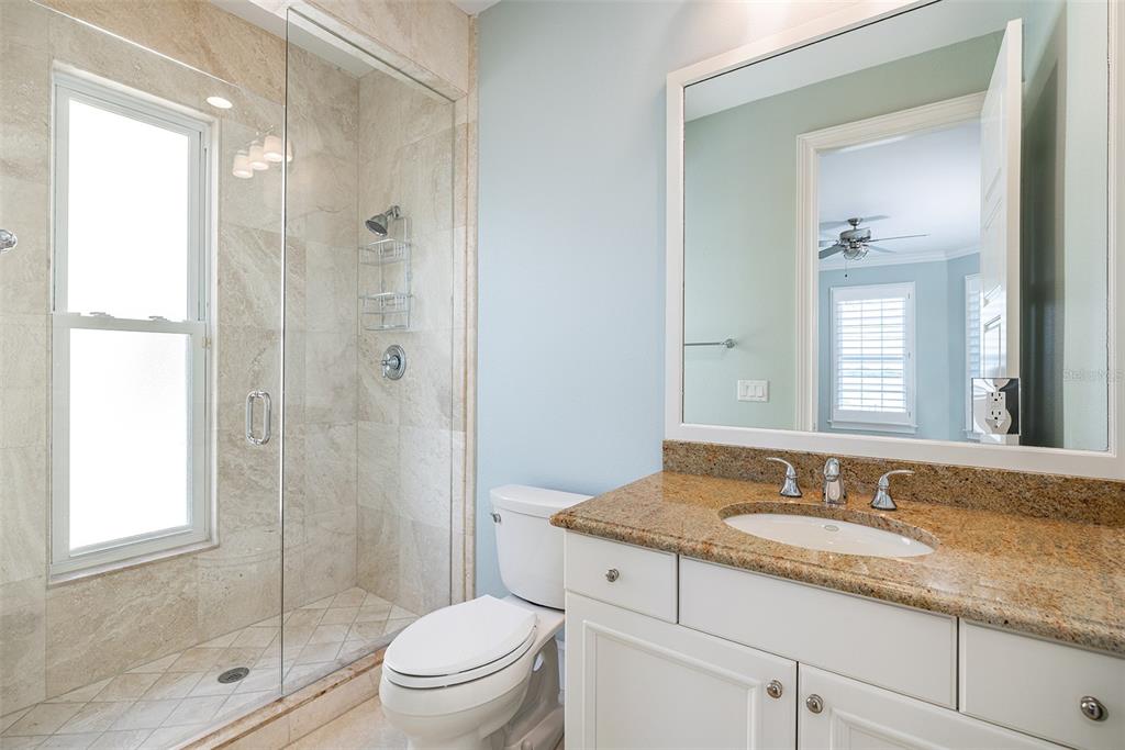821 Bay Point Drive Madeira Beach, FL 33708 - Photo 22 of 66 a bathroom with a granite countertop sink a mirror a shower and a toilet