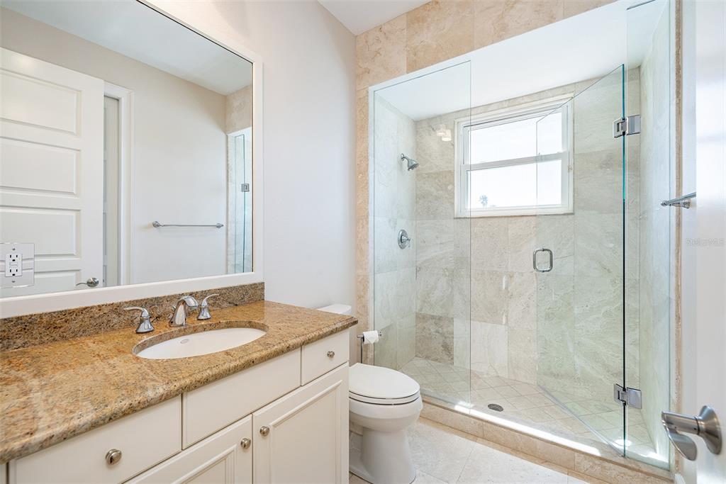 821 Bay Point Drive Madeira Beach, FL 33708 - Photo 42 of 66 a bathroom with a granite countertop sink a toilet and shower