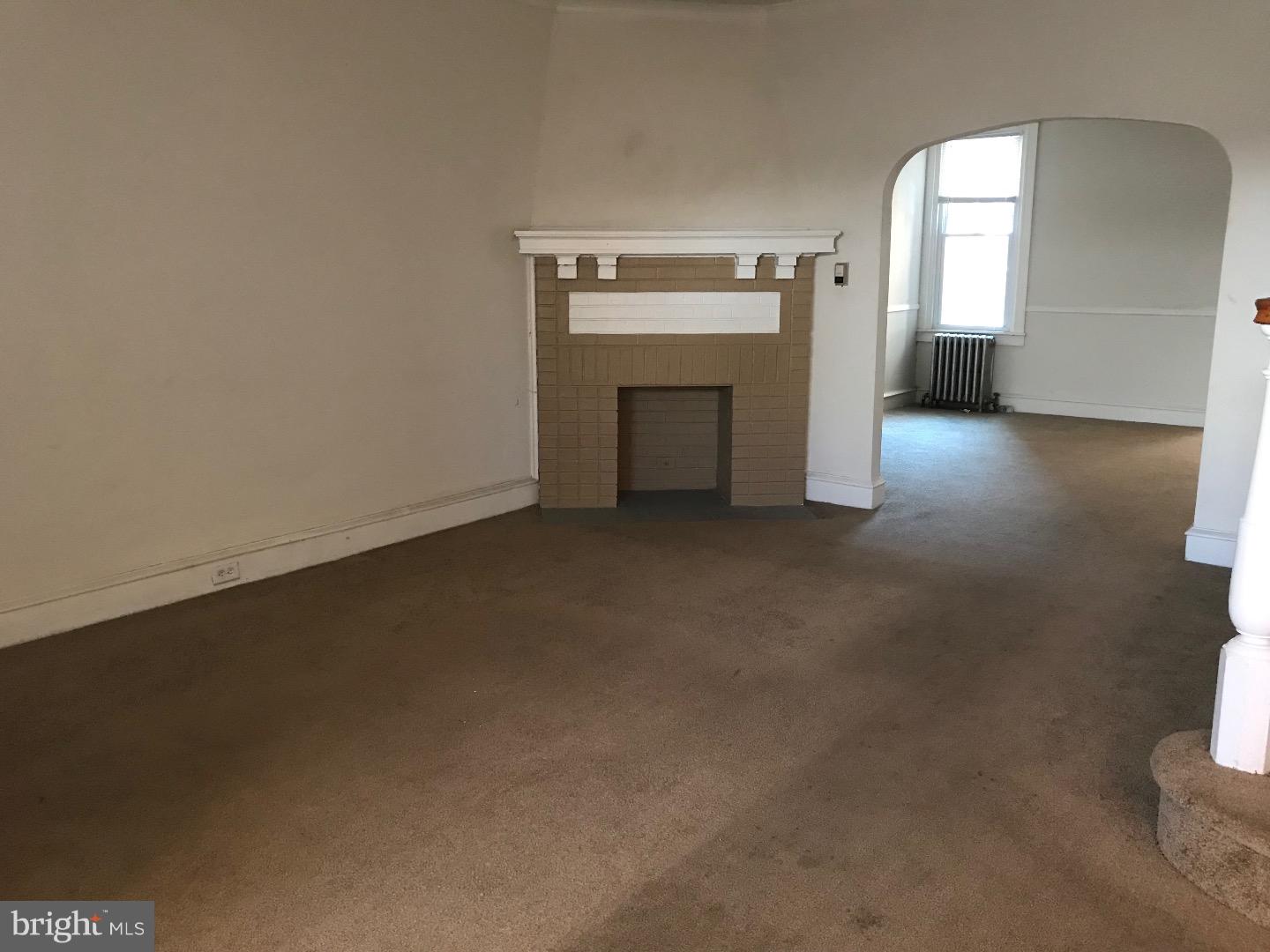 212 Wembly Road Upper Darby, PA 19082 - Photo 2 of 12 an empty room with a fireplace and windows