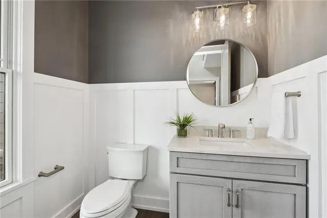 a bathroom with a toilet sink vanity and mirror