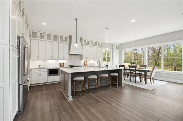 a kitchen with stainless steel appliances granite countertop dining table chairs stove and white cabinets