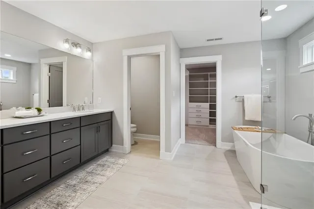 a spacious bathroom with a double vanity sink a large mirror and a bathtub