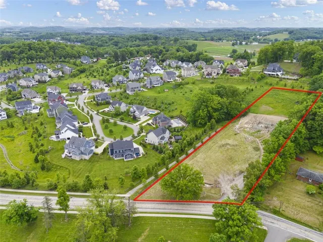 an aerial view of residential houses with outdoor space and trees