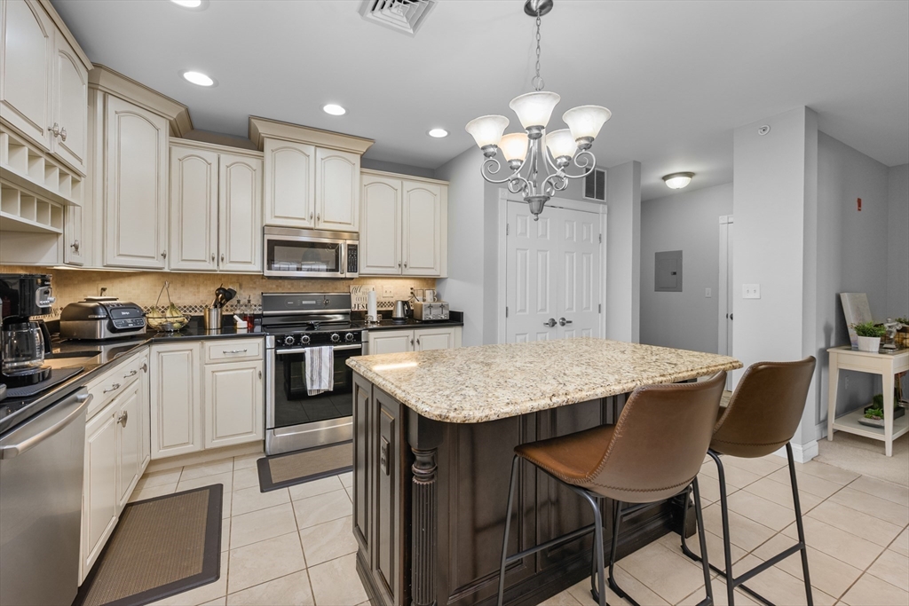68 Center Street, Unit 13 Barnstable, MA 02601 - Photo 4 of 29 a kitchen with stainless steel appliances granite countertop a stove top oven a refrigerator a sink dishwasher a dining table and chairs with wooden floor