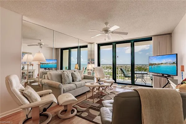 a living room with furniture floor to ceiling window and a flat screen tv