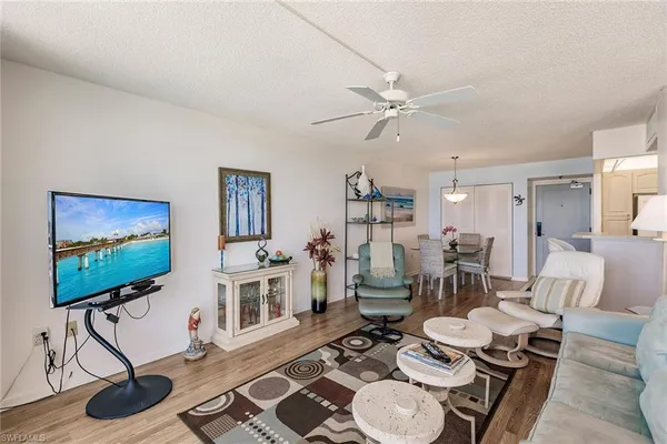 a living room with furniture a flat screen tv and a dining table with wooden floor