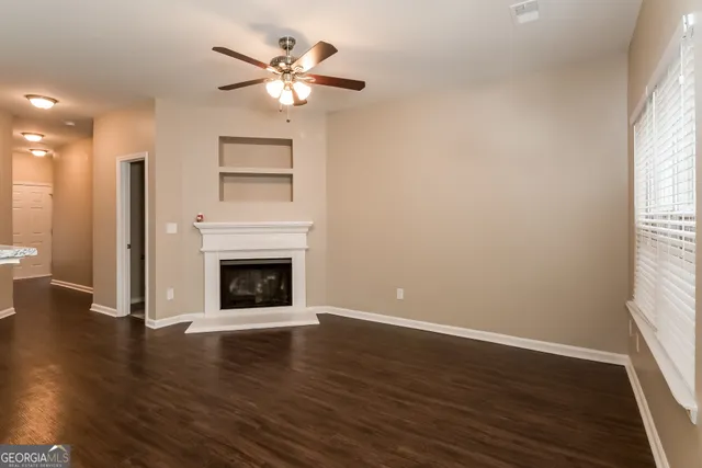 a view of a livingroom with a fireplace a ceiling fan and windows
