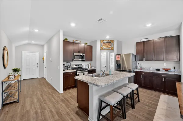 a kitchen with stainless steel appliances granite countertop a kitchen island hardwood floor sink stove dining table and chairs