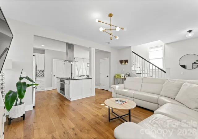 a living room with furniture kitchen view and a wooden floor