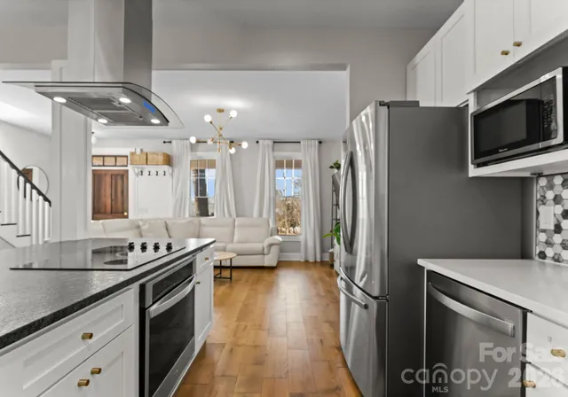 a kitchen with stainless steel appliances granite countertop a refrigerator a stove and a sink with wooden floor