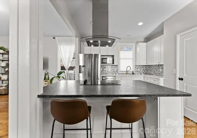 a kitchen with stainless steel appliances granite countertop a table and chairs in it