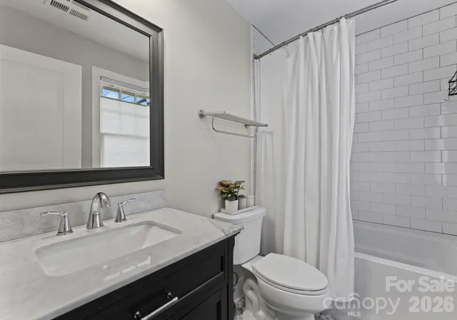 a bathroom with a granite countertop sink toilet a mirror and shower
