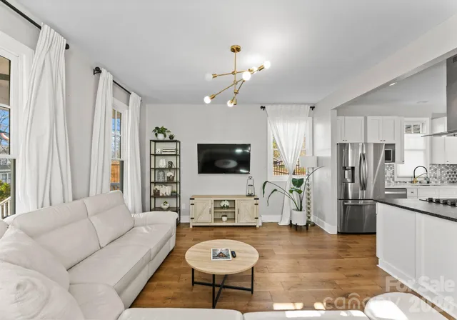 a living room with furniture a flat screen tv and kitchen view