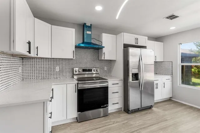 a kitchen with stainless steel appliances a refrigerator a sink and wooden floors