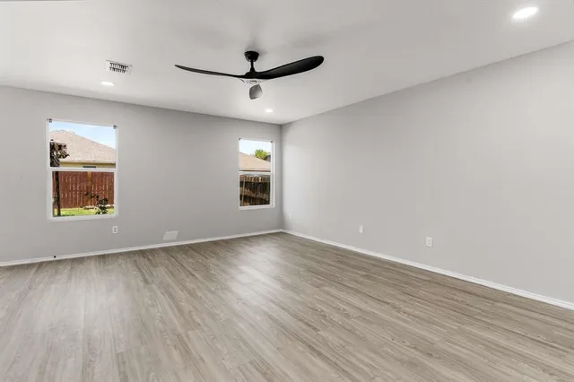 a view of an empty room with a window and wooden floor