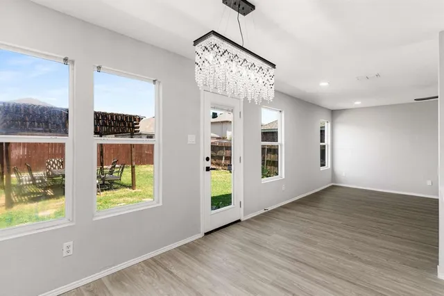 a view of an empty room with window and wooden floor