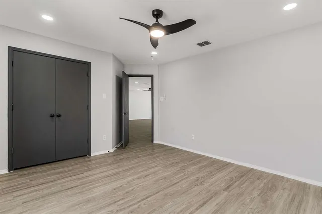 an empty room with wooden floor ceiling fan and windows