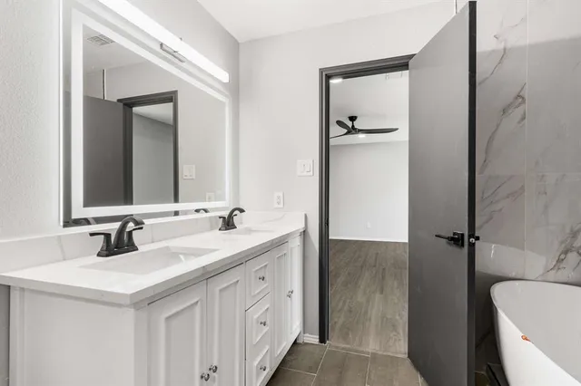 a bathroom with a double vanity sink mirror and bathtub
