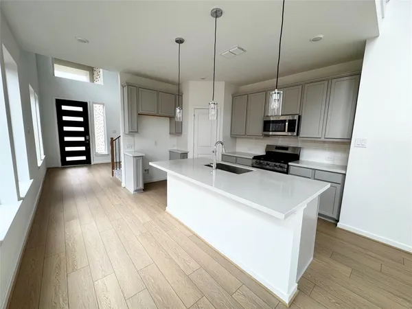 a kitchen with stainless steel appliances a white stove top oven a sink dishwasher and a refrigerator with wooden floor