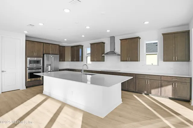 a kitchen with stainless steel appliances a sink and a stove top oven with wooden floor