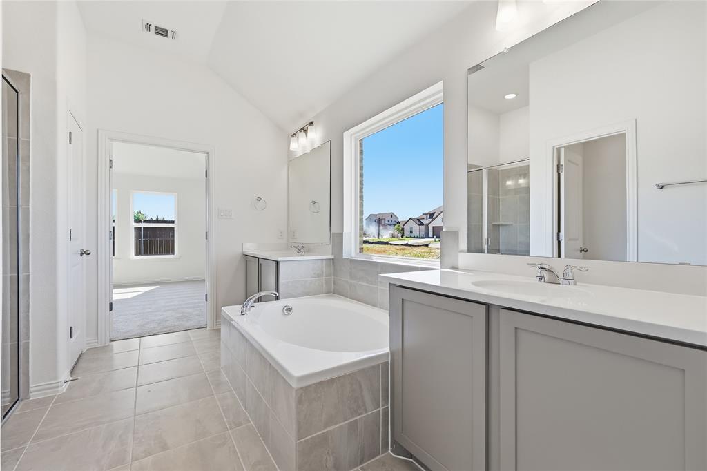 2529 Rivers W Road Anna, TX 75409 - Photo 26 of 40 Spacious bathroom featuring a built-in soaking tub, dual vanities with quartz countertops, a separate glass-enclosed shower, and tile flooring