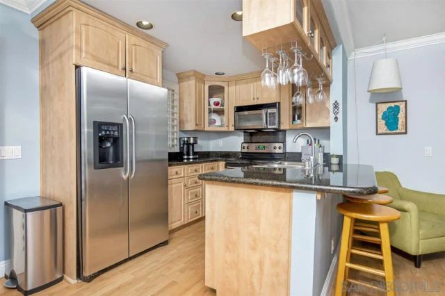 a kitchen with stainless steel appliances granite countertop a refrigerator a stove and a sink with wooden floor