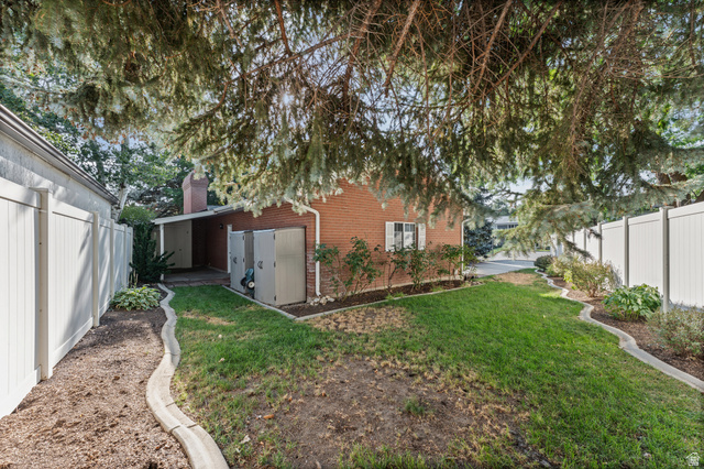 8441 Rua Branco Drive Sandy, UT 84093 - Photo 43 of 47 Brick exterior home featuring a spacious backyard with mature tree canopy, manicured lawn, curved hardscape edging, and detached garage structure