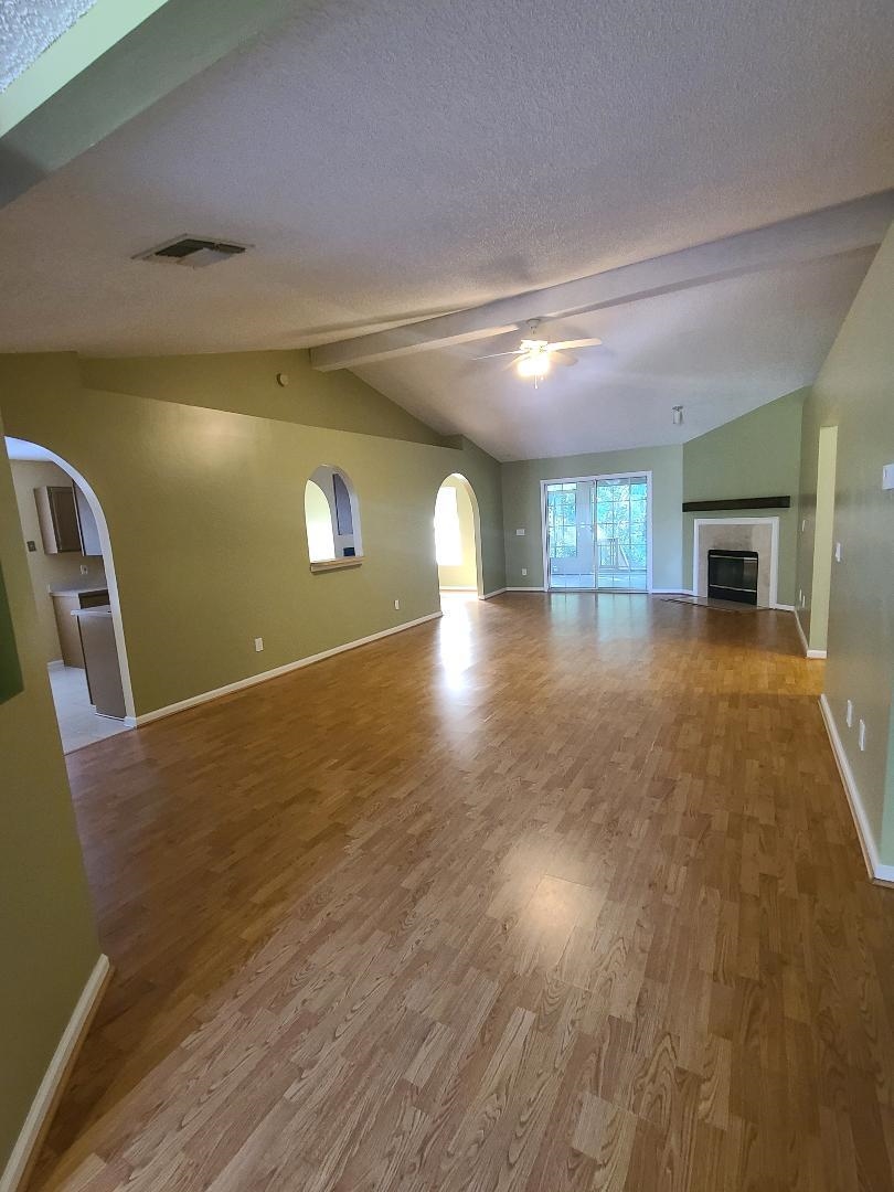 11996 Swooping Willow Road Jacksonville, FL 32223 - Photo 2 of 13 Unfurnished living room featuring arched walkways, wood finished floors, a fireplace, a textured ceiling, and ceiling fan