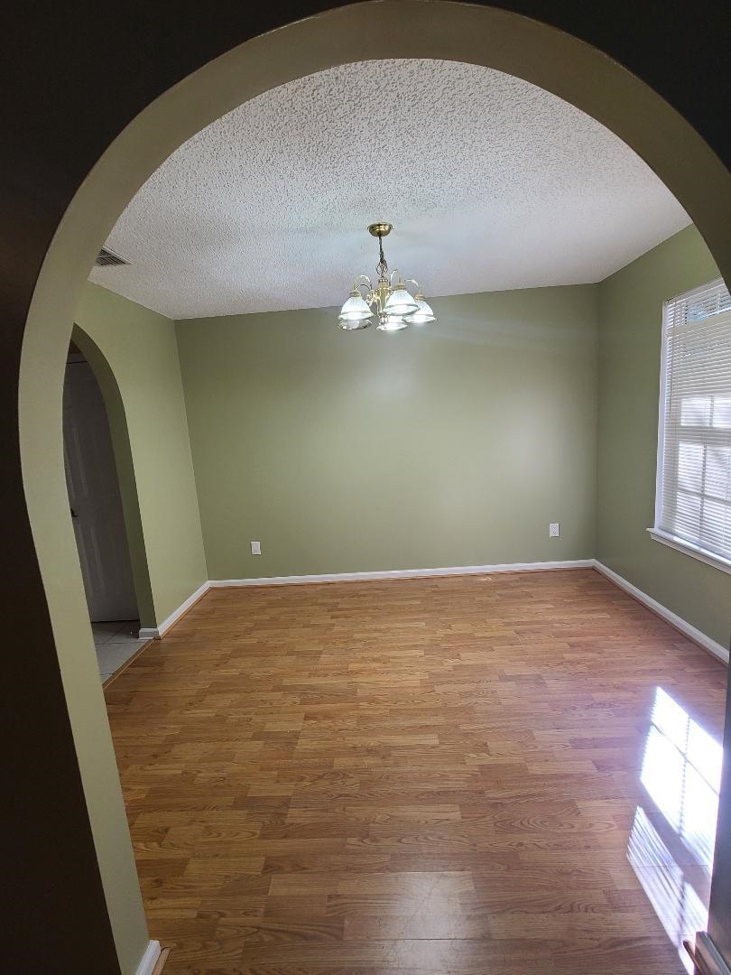 11996 Swooping Willow Road Jacksonville, FL 32223 - Photo 4 of 13 Unfurnished room featuring arched walkways, a textured ceiling, and wood finished floors