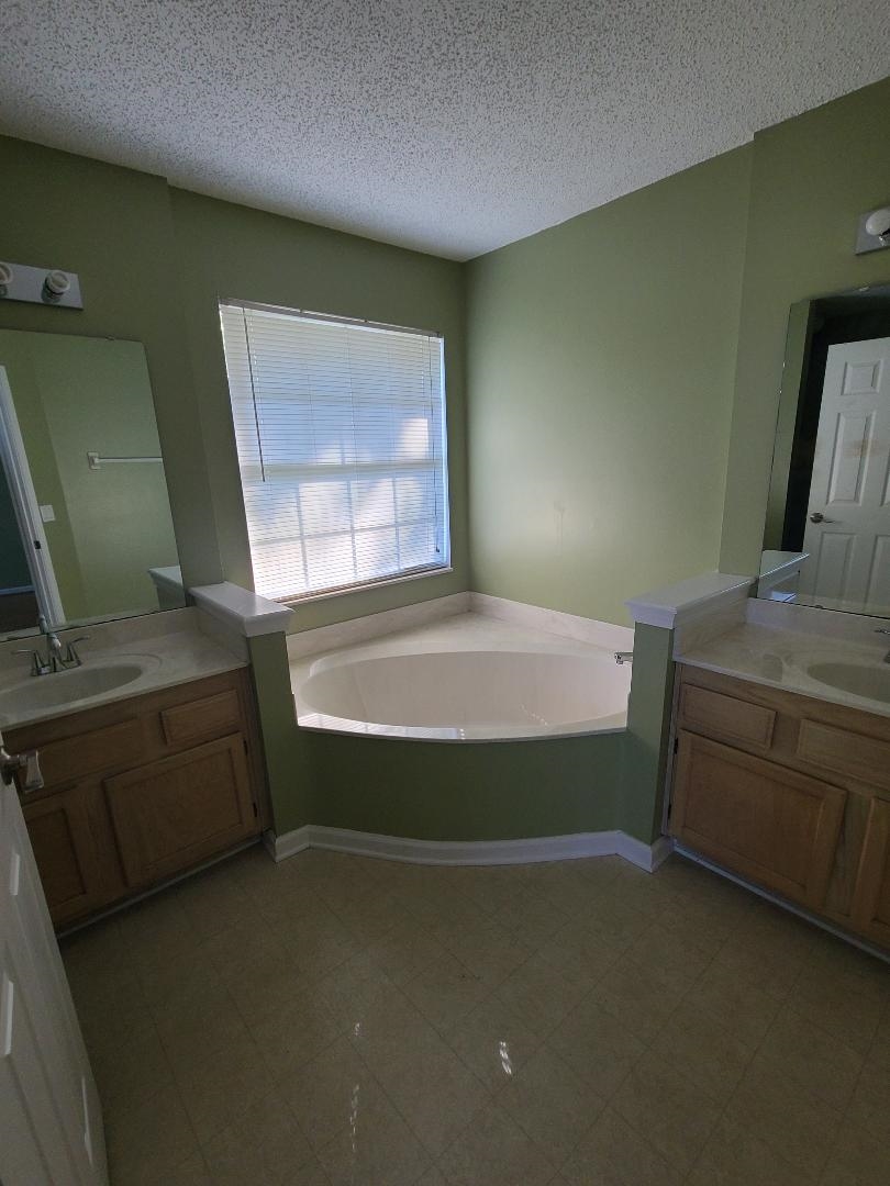 11996 Swooping Willow Road Jacksonville, FL 32223 - Photo 8 of 13 Bathroom with two vanities, a textured ceiling, and a garden tub