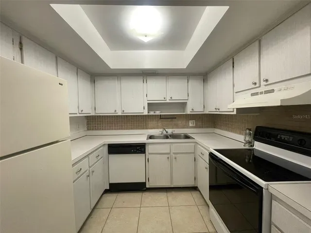 a kitchen with a sink dishwasher and white cabinets