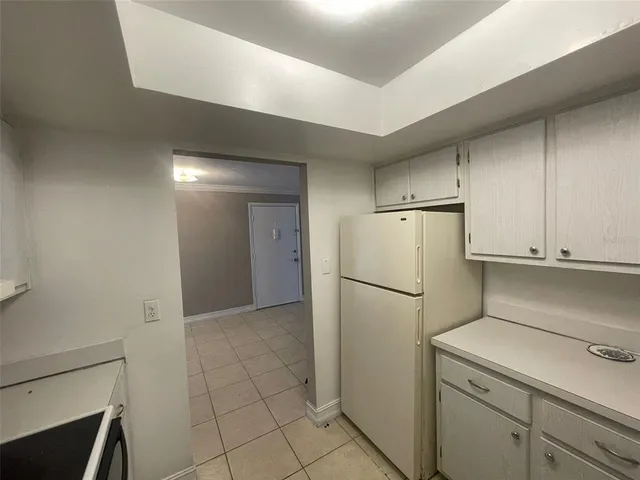 a view of a kitchen with refrigerator and white cabinets