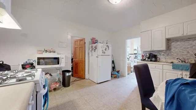a living room with furniture a flat screen tv and a refrigerator